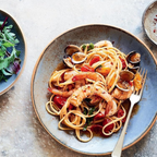 Plated dish of pasta with shrimp and clams on a textured surface
