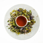 Tea cup surrounded by dried herbs on a marble surface