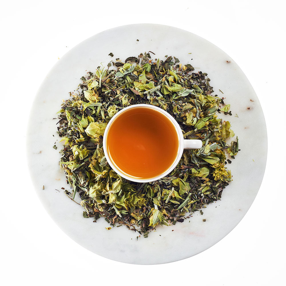 Tea cup with green tea leaves on a white plate