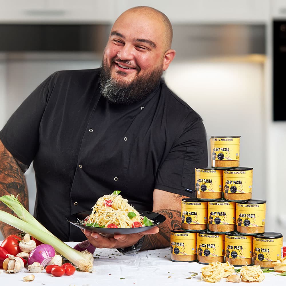 Man holding a pasta dish with Jolly Pasta tins in the background