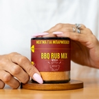 Jar of BBQ Rub Mix held by a person on a wooden surface