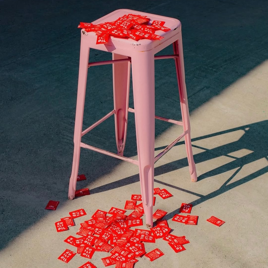Pink stool with scattered red packets on a dark surface