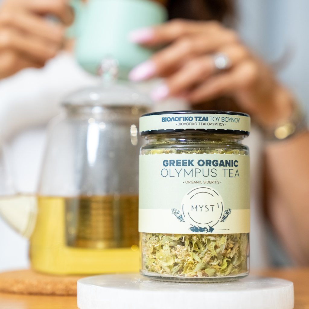 Jar of Greek organic Olympus tea with a blurred background of a person making tea.