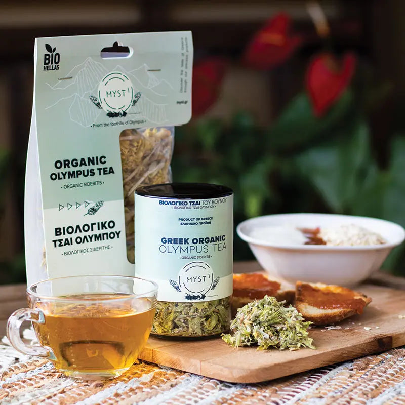 Greek organic Olympus tea packaging and a cup of tea on a wooden board with a blurred background.
